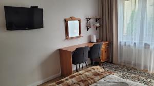 a hotel room with a desk and a television on the wall at Willa Jana in Nałęczów