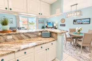 a kitchen with white cabinets and a dining room with a table at Private Beach, 2 Pools & Hot Tub in St. Petersburg
