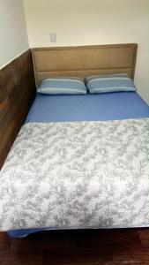 a bed with a blue and white blanket on it at Studio completo, perto da praia! in São Luís
