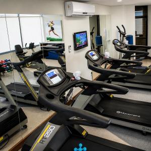 a gym with several treadmills and a row of exercise bikes at Hotel & Residence Sol Alphaville Flat in Barueri