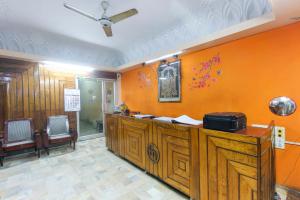 a lobby with an orange wall with a counter and chairs at Hotel O Maruthi in Salem
