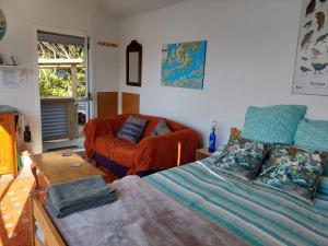 a bedroom with a bed and a couch and a chair at Endeavour View Eco Cabin in Endeavour Inlet