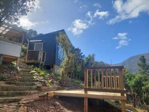 a wooden bench sitting in front of a house at Endeavour View Eco Cabin in Endeavour Inlet