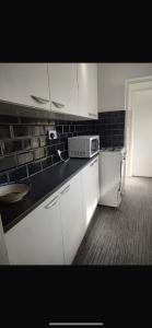 a kitchen with white cabinets and a microwave at Central stay in Nottingham