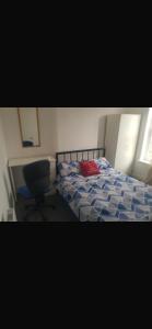 a bedroom with a bed with a red pillow and a chair at Central stay in Nottingham