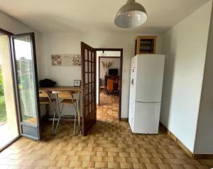 a kitchen with a table and a white refrigerator at Maison rurale 8 personnes in Saint-Hilaire-de-Court