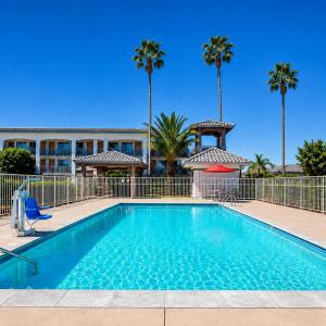 a swimming pool in front of a building with palm trees at TrueStay Inn in Bakersfield