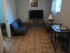 a living room with a tv and a chair and a table at Nice Guest House in Artesia