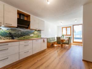 a kitchen with white cabinets and a dining room with a table at Grünbichel Hof I in Uttendorf