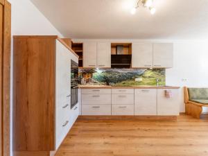 a kitchen with white cabinets and wooden floors at Grünbichel Hof II in Uttendorf