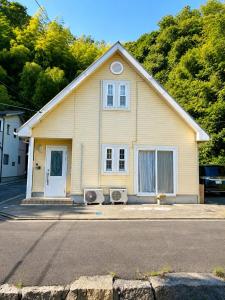 a yellow house on the side of a street at しまなみ海道-愛犬と泊まれる一棟貸し-本格バレルサウナ-ドッグラン-BBQ完備-YOSHIUMi in Imabari