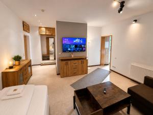 a living room with a couch and a flat screen tv at Waldgasthaus & Berghotel Steinerne Renne in Wernigerode