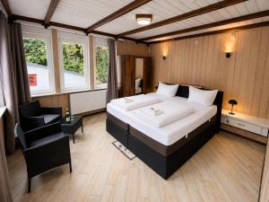 a bedroom with a large bed and a chair at Waldgasthaus & Berghotel Steinerne Renne in Wernigerode