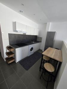 a kitchen with white cabinets and a table with stools at Le Canetois in Canet-en-Roussillon