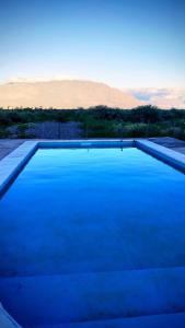 a blue swimming pool with a mountain in the background at Cabañas "Los Elementos", San Carlos, Salta, in San Carlos