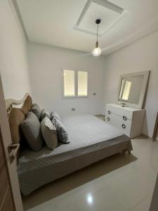 a bedroom with a bed and a dresser and a mirror at Triplex résidence tilel chott mariem in Sousse