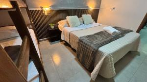 a small room with two beds and a chair at Apto 05 - A&N Estadia Premium - Centro Bandeirantes PR in Bandeirantes
