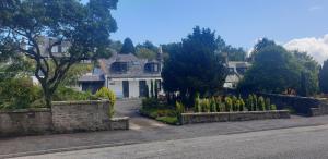 a house with a stone fence and a yard at Lily Bank Room in Stonehaven