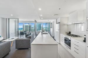 a kitchen with white cabinets and a living room at Q1 Resort & Spa - Official in Gold Coast