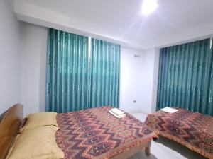 a bedroom with two beds and green curtains at Apartamentos Pachatusan in Pisac +3 photos