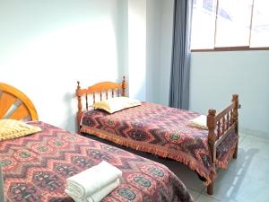 two beds sitting next to each other in a room at Apartamentos Pachatusan in Pisac
