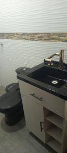 a bathroom with a black sink and a toilet at Los Ceibos Hostal in Montecristi