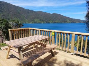 a wooden bench on a deck with a view of the water at Endeavour View Eco Cabin in Endeavour Inlet