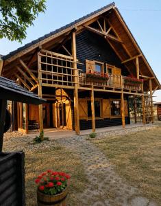 a large wooden house with a balcony and flowers at Komondor Vendégház in Vácrátót