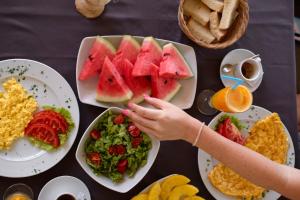 a person reaching for a slice of watermelon on a table with food at Hotel Adrović in Sveti Stefan