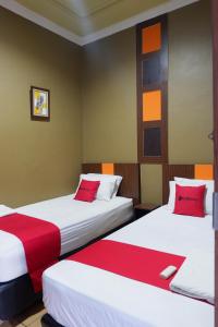 two beds in a room with red and white sheets at Hy ReDz in Palopo