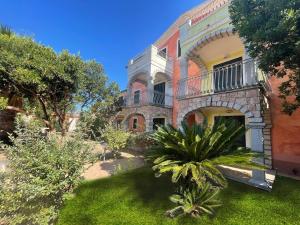 an old house with a palm tree in front of it at Appartamento Eli in Valledoria