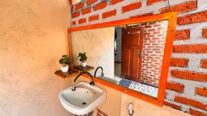 a bathroom with a sink in front of a brick wall at Sunset Cottages in Hitokalak