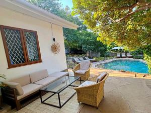 a patio with a couch and chairs next to a pool at Palm Villa Hideaway in Diani Beach
