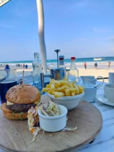 a hamburger and french fries on a table at the beach at Palm Villa Hideaway in Diani Beach