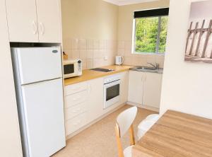 a kitchen with a white refrigerator and a table at Robe Sunset Apartments in Robe