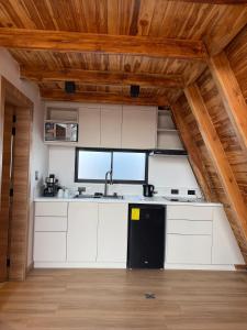a kitchen with white cabinets and a black refrigerator at Helite Arena y Mar in Puerto Cayo