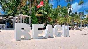 a large white sign on a beach with palm trees at Beach Pool Hotel Punta Cana in Punta Cana +35 photos