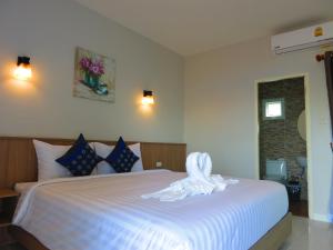 a bedroom with a white bed with a towel on it at Winrisa Place in Nai Yang Beach