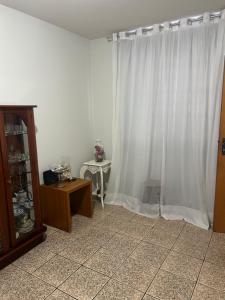 a living room with white curtains and a table at Apartamento simples no centro de Lavras com garagem in Lavras