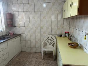 a kitchen with a table and a white chair in it at Apartamento simples no centro de Lavras com garagem in Lavras