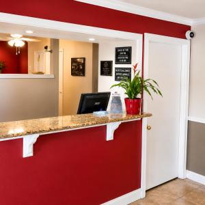 a room with a red wall and a counter with a potted plant at TrueStay Inn in Bakersfield