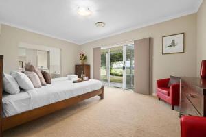 a bedroom with a large bed and a red chair at Mole Hill Farmhouse in Lovedale +20 photos