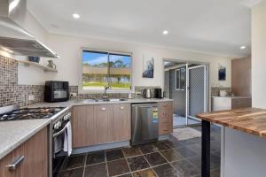 a kitchen with wooden cabinets and a stove top oven at Andres Farm Cottage in Broke +24 photos