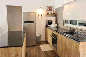 a kitchen with a stainless steel refrigerator and wooden cabinets at Cottage Manua in Temae