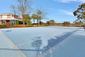 an empty tennis court in front of a house at Beggars Bridge Vineyard Homestead with pool and tennis in Rothbury