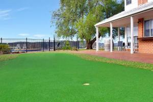 a golf ball laying on a green lawn in front of a house at Beggars Bridge Vineyard Homestead with pool and tennis in Rothbury