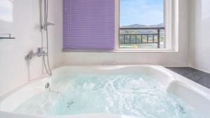 a bath tub in a bathroom with a window at Gapyeong Rialto Pension in Gapyeong