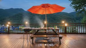 a table with an orange umbrella on a deck at Gapyeong Rialto Pension in Gapyeong