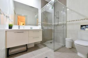 a white bathroom with a shower and a toilet at King 2 - close proximity to Bimbadgen and Hope Estate concerts in Pokolbin