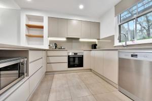 a large kitchen with white cabinets and appliances at Villa 3br Malbec Villa located within Cypress Lakes Resort in Pokolbin